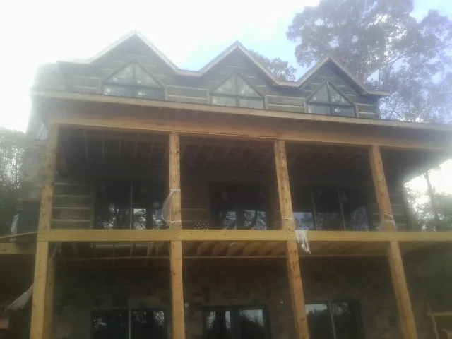 Dormers and porch framing on a large log home under construction — Roof Coating work by our crew in Rainsville