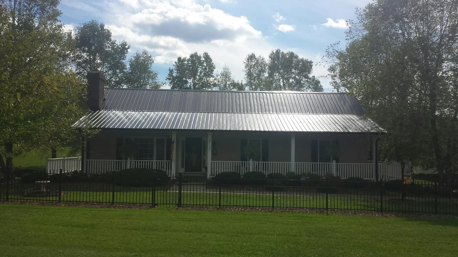 Gray metal roof on a brick ranch with a full width front porch — Gutter Guard Installation work by our crew in Rainsville