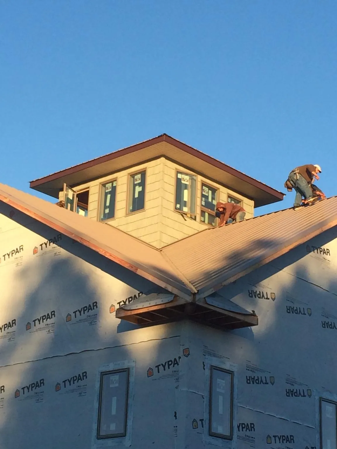 Roofers working around a rooftop cupola on a new metal roof at sunset — Roof Waterproofing in Rainsville by Roofing Brothers